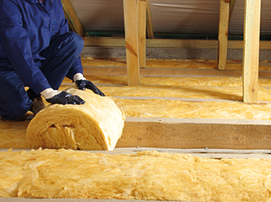 tradesperson rolling a roll of loft insulation